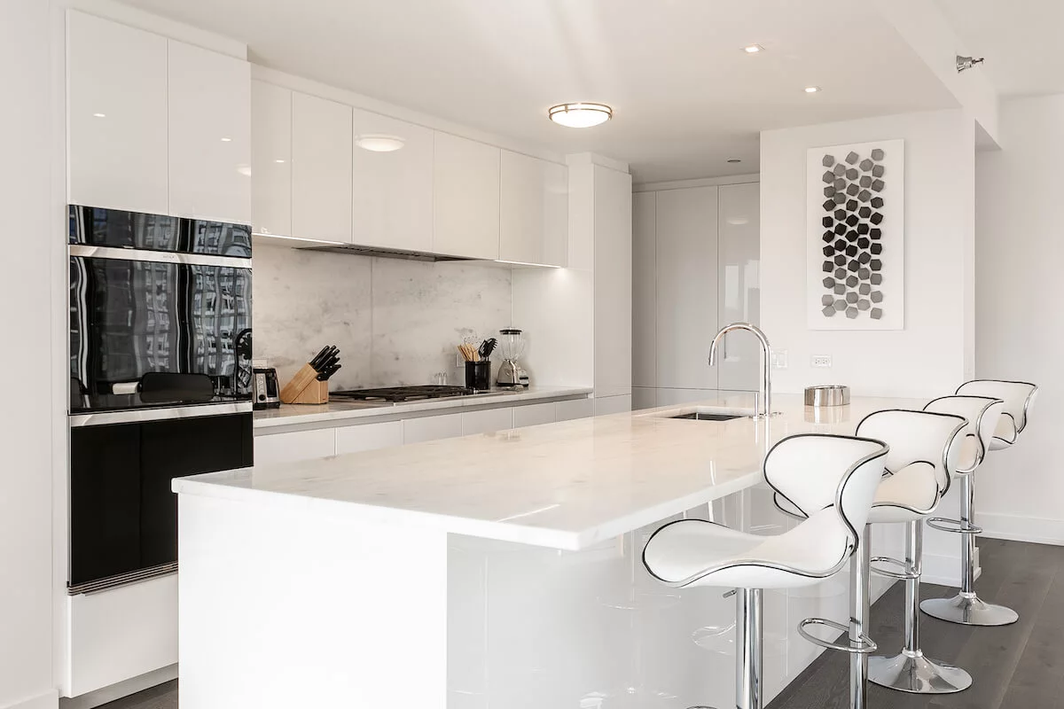 Luxury furnished apartment kitchen in downtown Chicago with modern white cabinets and a marble island.